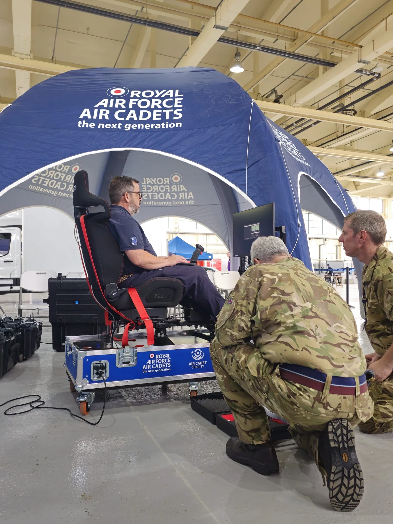 A cadet trainer demonstrating the portable motion simulator while RAF personnel observe